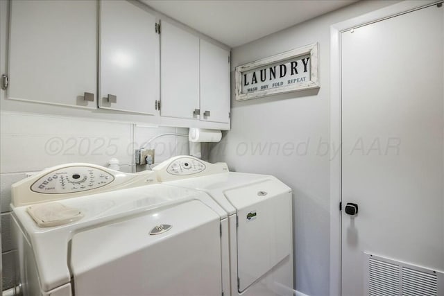 washroom featuring visible vents, washing machine and clothes dryer, and cabinet space