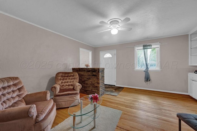 living area featuring light wood-style floors, baseboards, crown molding, and ceiling fan