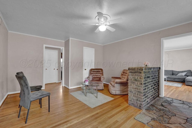 living area with light wood-style floors, baseboards, ornamental molding, and a ceiling fan