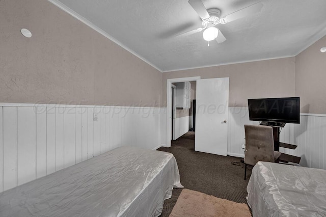 bedroom with a wainscoted wall, dark colored carpet, a ceiling fan, lofted ceiling, and ornamental molding