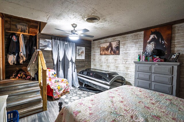 713 N Dwight St, Pampa, TX 79065 - bedroom featuring a ceiling fan, a textured ceiling, visible vents, wood walls, and wood finished floors