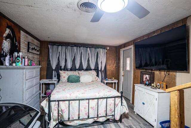 713 N Dwight St, Pampa, TX 79065 - bedroom featuring a textured ceiling, wood walls, a ceiling fan, wood finished floors, and visible vents