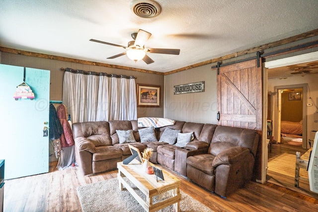 713 N Dwight St, Pampa, TX 79065 - living area with ceiling fan, a barn door, a textured ceiling, wood finished floors, and visible vents