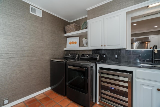 3220 S Travis St, Amarillo, TX 79109 - laundry area featuring wine cooler, cabinet space, crown molding, washer and clothes dryer, and light tile patterned floors