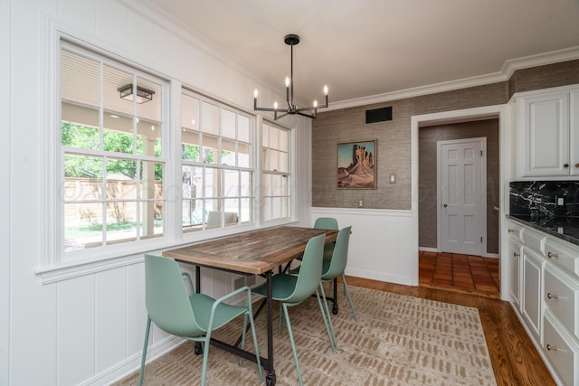 3220 S Travis St, Amarillo, TX 79109 - dining area featuring a chandelier, crown molding, wood finished floors, wainscoting, and a decorative wall