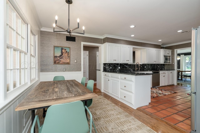 3220 S Travis St, Amarillo, TX 79109 - kitchen featuring appliances with stainless steel finishes, dark countertops, crown molding, white cabinets, and a chandelier