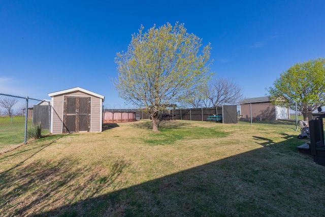 view of yard featuring a storage shed, a fenced backyard, and an outbuilding
