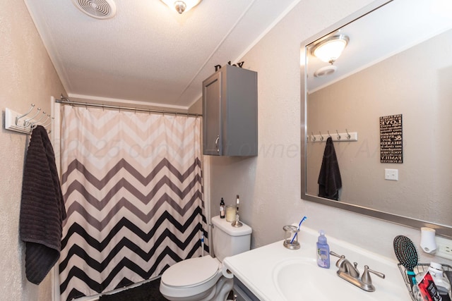 bathroom featuring visible vents, toilet, vanity, and a textured wall