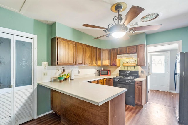 kitchen featuring kitchen peninsula, black appliances, tasteful backsplash, dark hardwood / wood-style floors, and ceiling fan