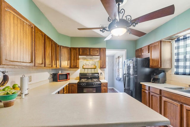 kitchen featuring kitchen peninsula, sink, black appliances, and decorative backsplash