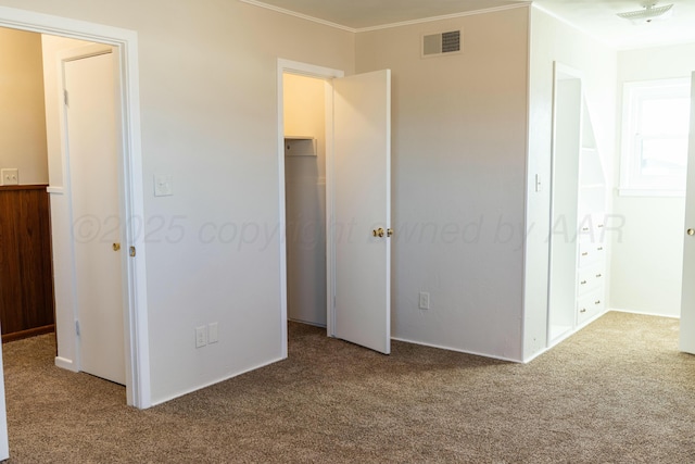 unfurnished bedroom with crown molding, carpet, and visible vents