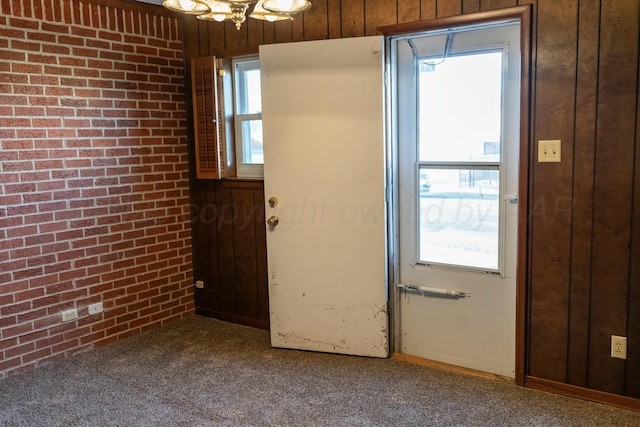 doorway featuring carpet flooring and brick wall