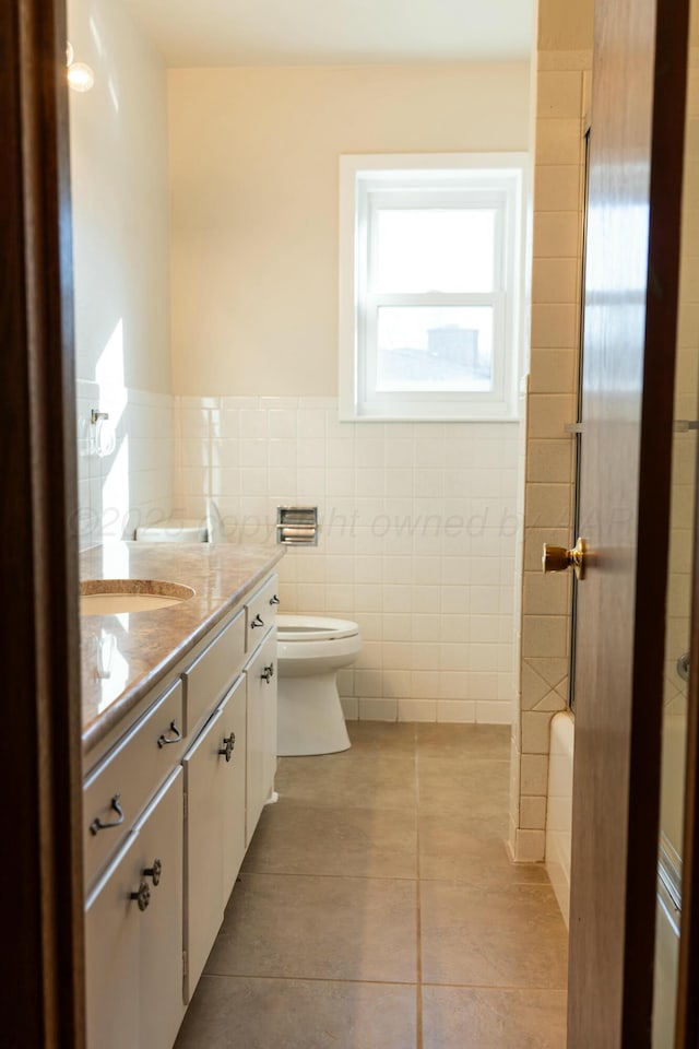 bathroom with tile patterned floors, vanity, toilet, and tile walls