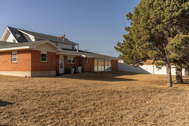 rear view of property with central AC unit and a yard