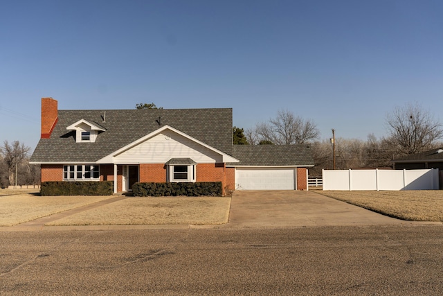 cape cod-style house with driveway, a chimney, a garage, brick siding, and fence