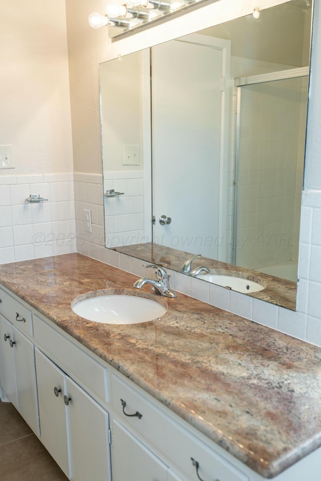 bathroom featuring a shower with door, vanity, tile patterned flooring, and tile walls