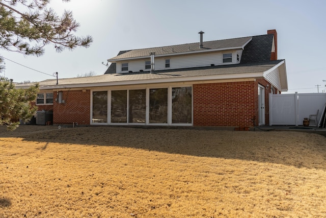 rear view of house featuring cooling unit and a lawn