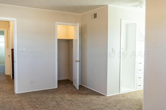 unfurnished bedroom with crown molding, carpet flooring, and a spacious closet