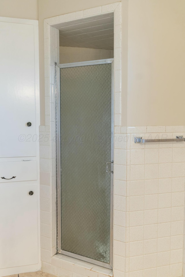 bathroom with a shower with shower door and tile walls