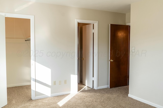 unfurnished bedroom featuring light colored carpet, a closet, and a walk in closet