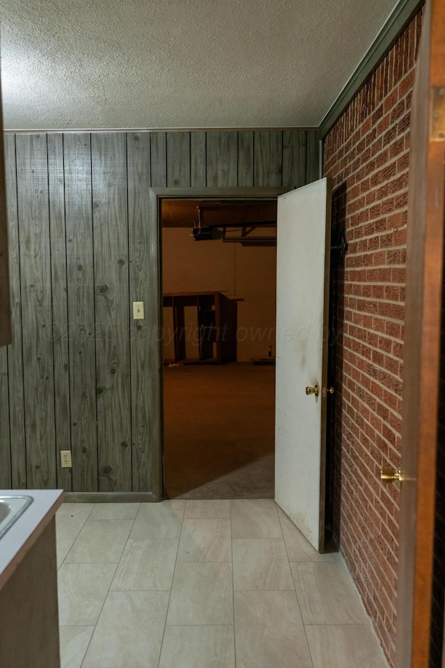 tiled spare room featuring wood walls, a textured ceiling, and brick wall