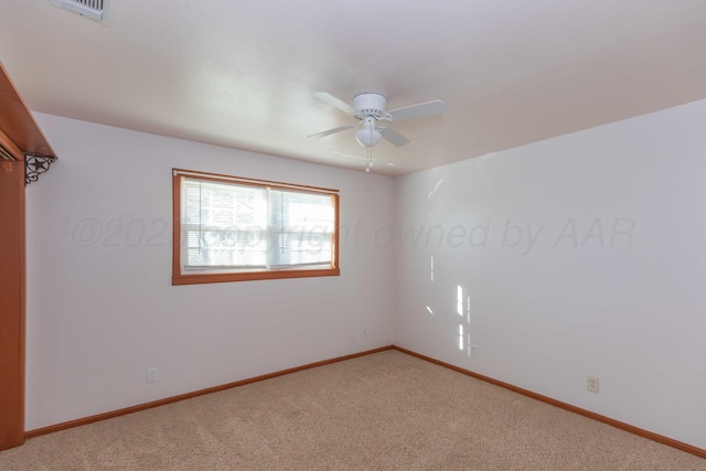 unfurnished room featuring carpet floors, baseboards, visible vents, and a ceiling fan