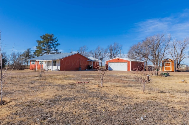 view of side of home featuring metal roof, driveway, an outdoor structure, and a detached garage