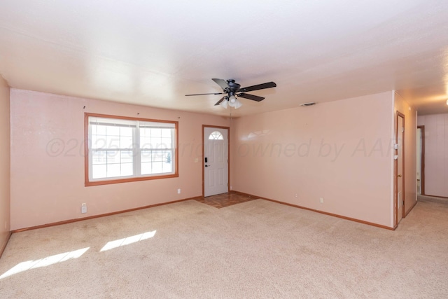 carpeted spare room featuring baseboards, visible vents, and a ceiling fan