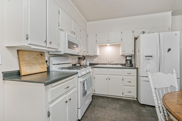 5222 S Travis St, Amarillo, TX 79110 - kitchen with white appliances, dark countertops, white cabinets, and a textured ceiling