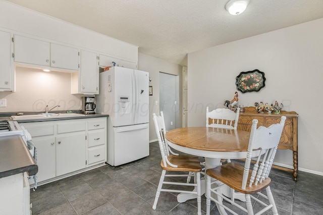 5222 S Travis St, Amarillo, TX 79110 - kitchen featuring white refrigerator with ice dispenser, white cabinets, dark countertops, a textured ceiling, and stove