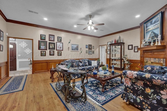 5105 Black Oak Dr, Amarillo, TX 79110 - living area featuring a wainscoted wall, a ceiling fan, light wood-style flooring, crown molding, and a textured ceiling