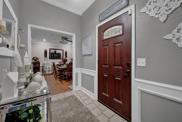 5105 Black Oak Dr, Amarillo, TX 79110 - foyer featuring crown molding, a ceiling fan, light tile patterned floors, wainscoting, and a decorative wall