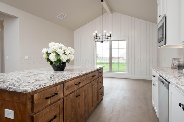 kitchen featuring light stone countertops, a notable chandelier, appliances with stainless steel finishes, vaulted ceiling with beams, and wood finished floors