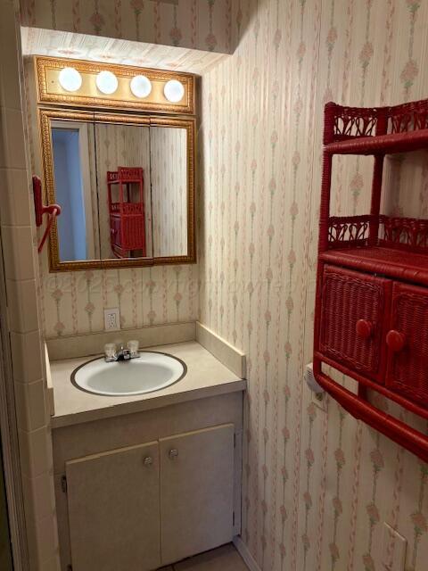 bathroom with wallpapered walls and vanity