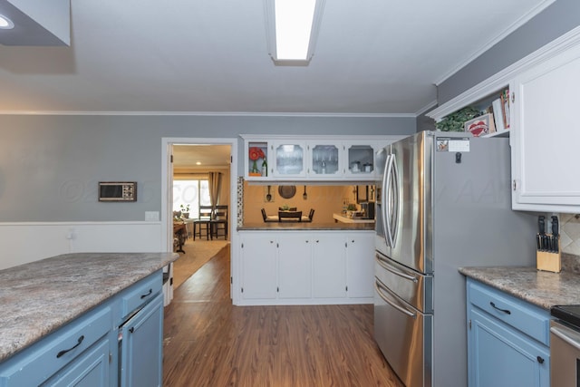 407 Thompson Ln, Canyon, TX 79015 - kitchen featuring freestanding refrigerator, ornamental molding, dark wood-type flooring, white cabinetry, and blue cabinetry