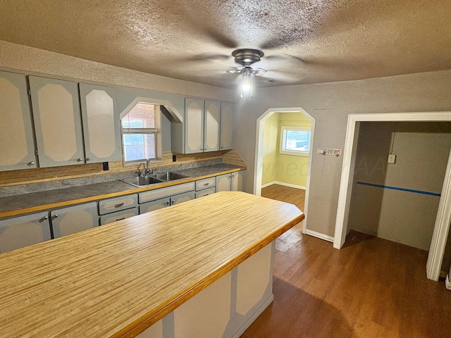 605 E 4th St, Panhandle, TX 79068 - kitchen with a sink, arched walkways, a ceiling fan, dark wood-type flooring, and a textured ceiling