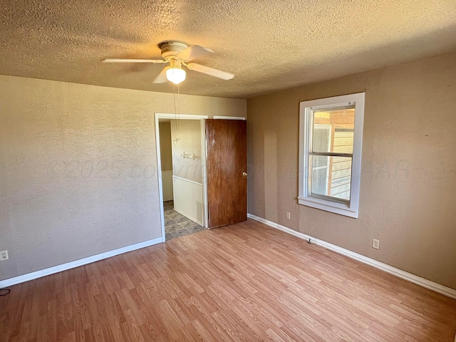 605 E 4th St, Panhandle, TX 79068 - unfurnished bedroom with wood finished floors, baseboards, a textured wall, a textured ceiling, and ceiling fan