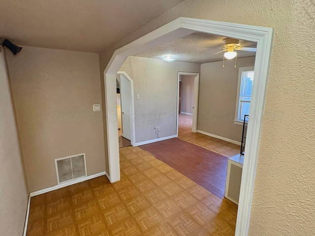 605 E 4th St, Panhandle, TX 79068 - spare room featuring a ceiling fan, a textured wall, parquet flooring, baseboards, and a textured ceiling