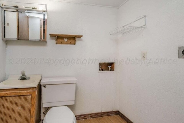 bathroom featuring toilet, vanity, baseboards, and wood finished floors