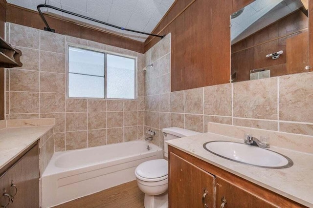 full bathroom with toilet, vanity,  shower combination, lofted ceiling, and tile walls