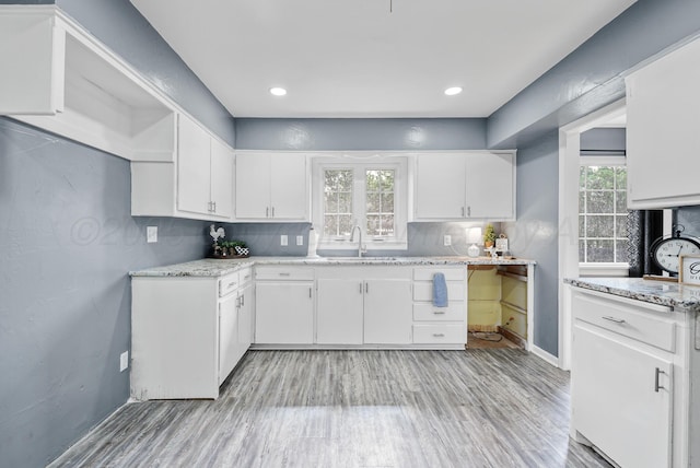 3701 Westlawn Ave, Amarillo, TX 79102 - kitchen featuring white cabinetry, light wood-style flooring, light stone counters, and decorative backsplash