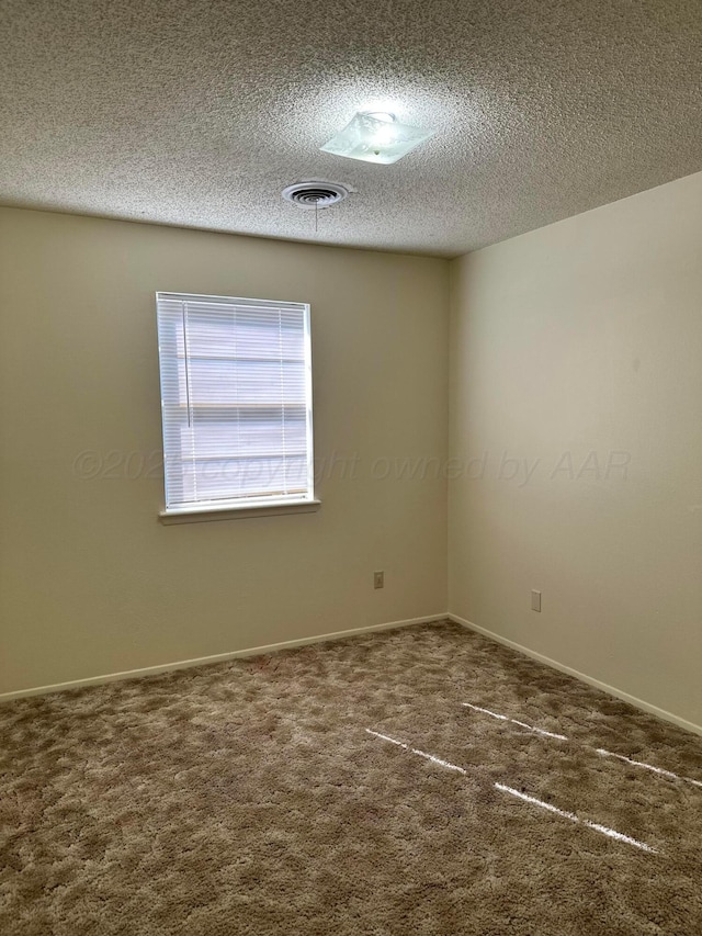 carpeted empty room with a textured ceiling