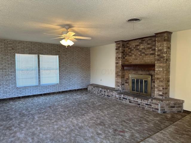 unfurnished living room with brick wall, a fireplace, dark colored carpet, ceiling fan, and a textured ceiling