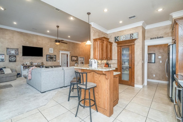 212 Cimarron St, Borger, TX 79007 - kitchen featuring freestanding refrigerator, a breakfast bar, light tile patterned flooring, open floor plan, and a peninsula