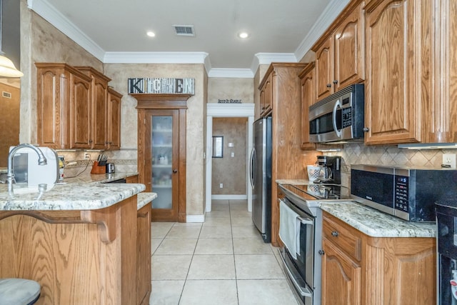 212 Cimarron St, Borger, TX 79007 - kitchen featuring appliances with stainless steel finishes, a sink, a breakfast bar area, light stone countertops, and crown molding