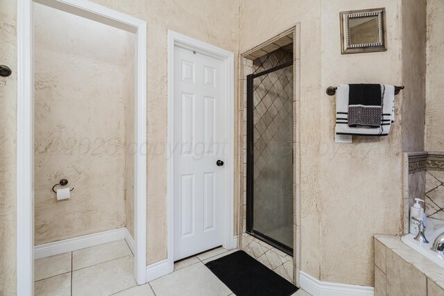 212 Cimarron St, Borger, TX 79007 - bathroom featuring a stall shower, tile patterned floors, a relaxing tiled tub, and baseboards