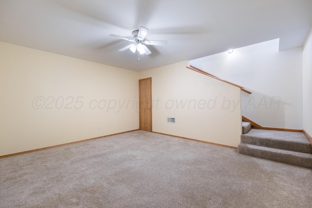 carpeted spare room featuring stairway, baseboards, visible vents, and a ceiling fan