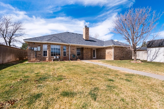 rear view of property with fence, a yard, an outdoor structure, brick siding, and a chimney