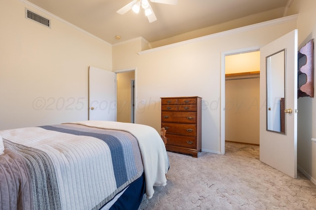 bedroom featuring visible vents, a walk in closet, ornamental molding, light colored carpet, and ceiling fan