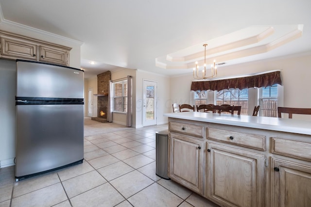 kitchen with a chandelier, a healthy amount of sunlight, freestanding refrigerator, and a tray ceiling